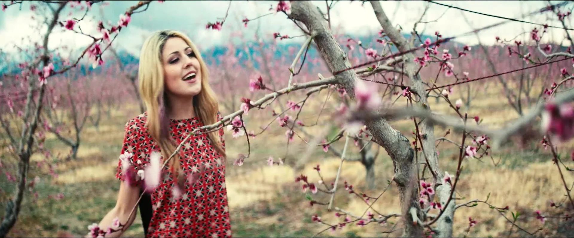 The singer among blossoming trees in a scene from the music video Be Mine.