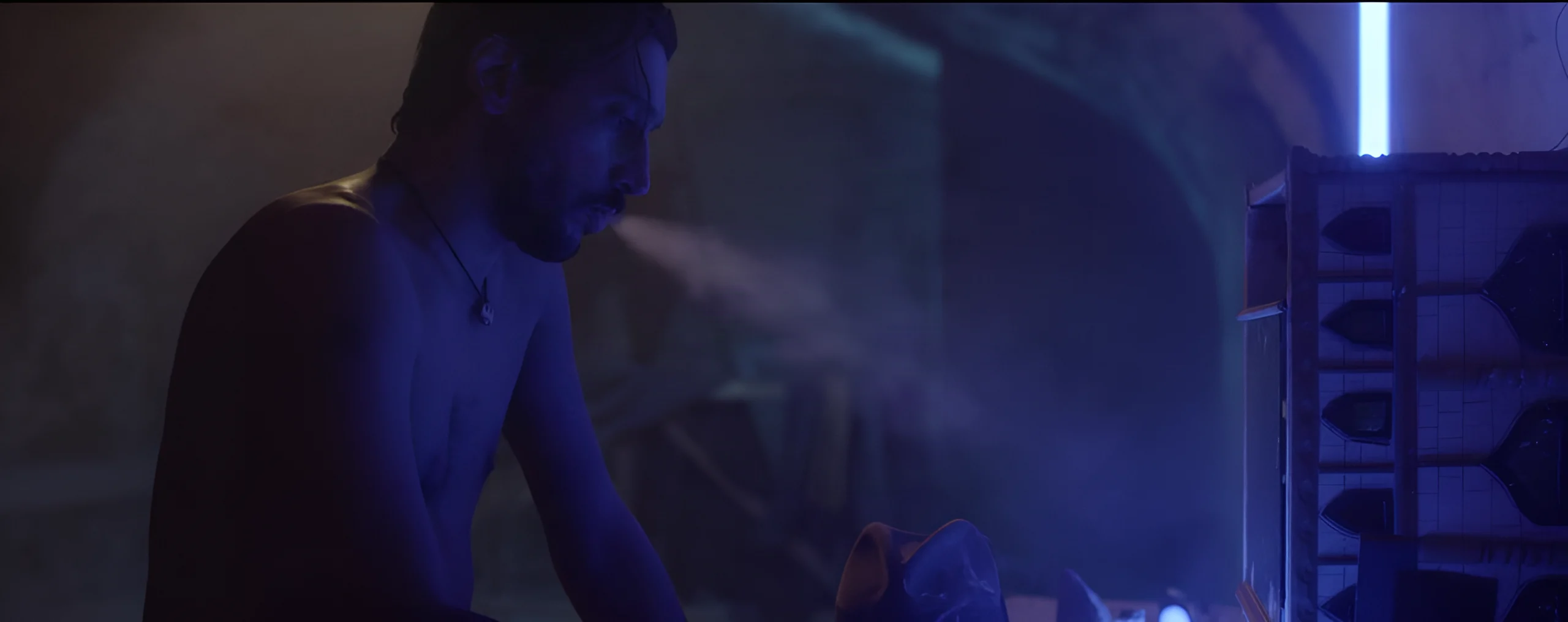 A person at a drum kit, lit by blue light, in a scene from La leggenda di Bob Wind.