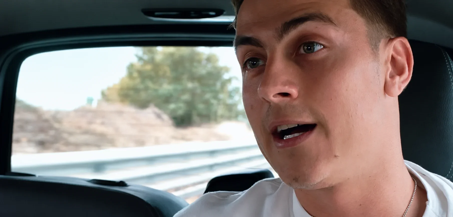 Close-up of the protagonist sitting in a car, with the landscape outside the window, in Champions of Made in Italy.